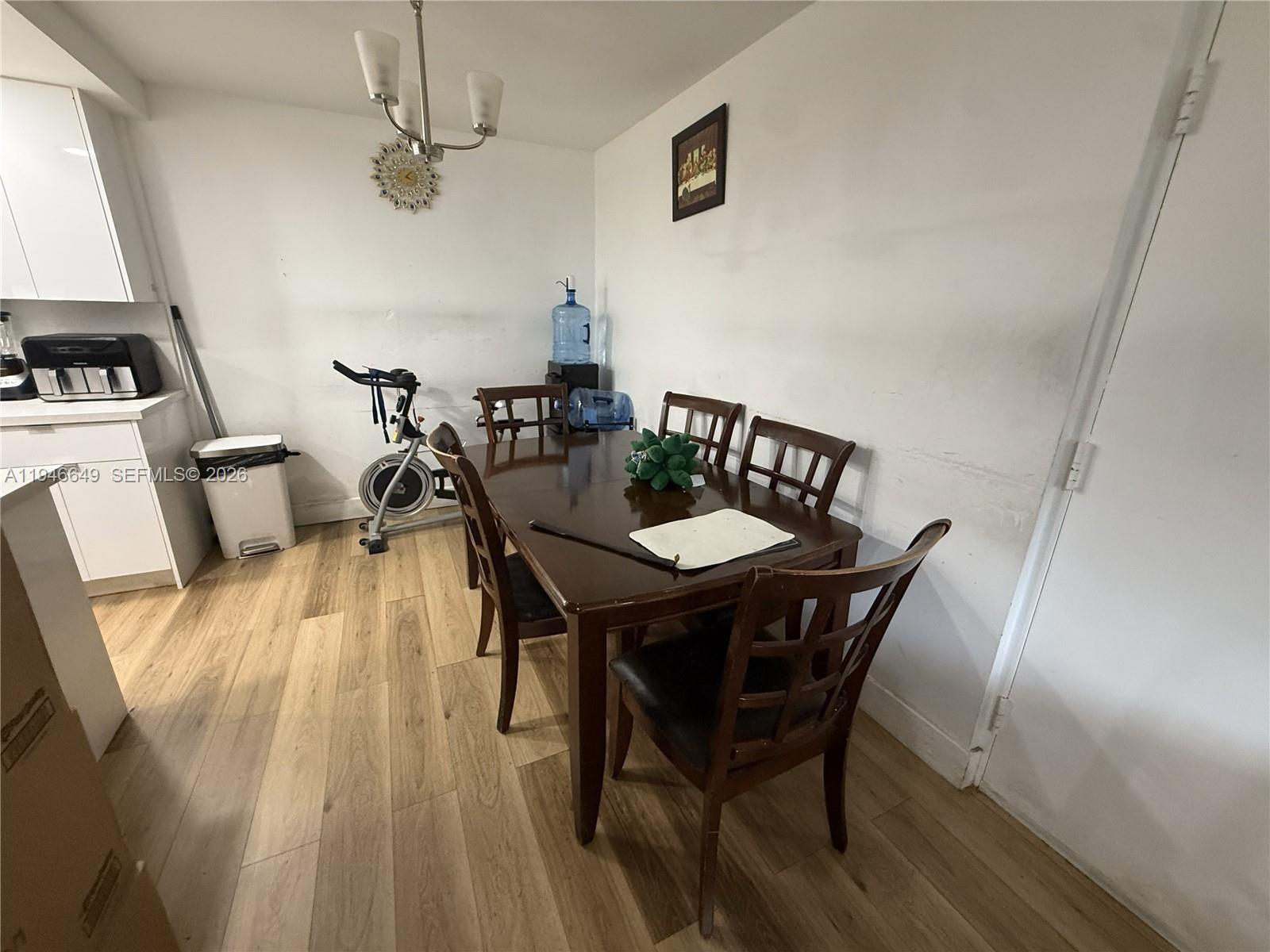 A dining area features a dark wood table with chairs, light flooring, and a stationary bike — 10822 N Kendall Dr # S23, Miami FL 33176, MIAMI, FL