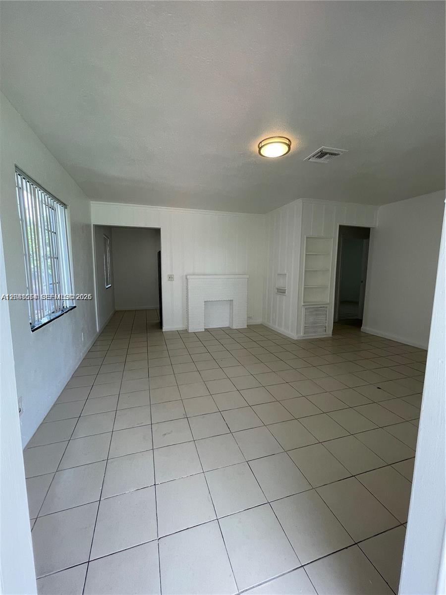 This living room features white walls, a fireplace, and light-colored tile flooring — 2435 Plunkett St # 1, Hollywood FL 33020, HOLLYWOOD, FL