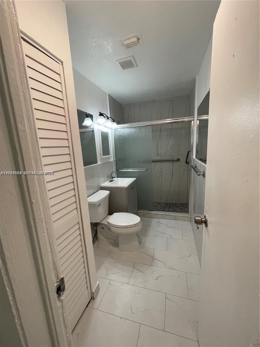 A bathroom features white marble-look floor tiles, a pedestal sink, a toilet, and a glass-enclosed shower — 2435 Plunkett St # 1, Hollywood FL 33020, HOLLYWOOD, FL