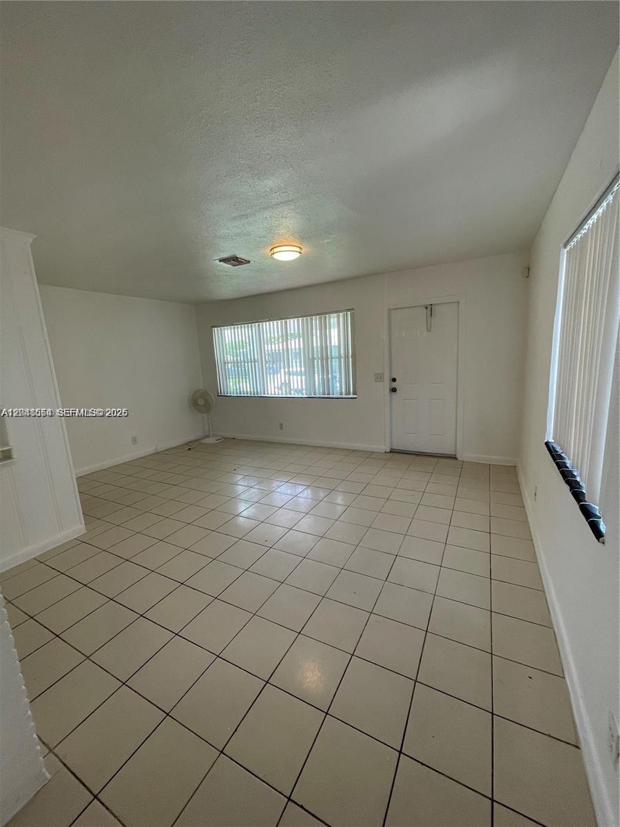 An empty room features white walls, a tiled floor, a ceiling light, and two windows — 2435 Plunkett St # 1, Hollywood FL 33020, HOLLYWOOD, FL