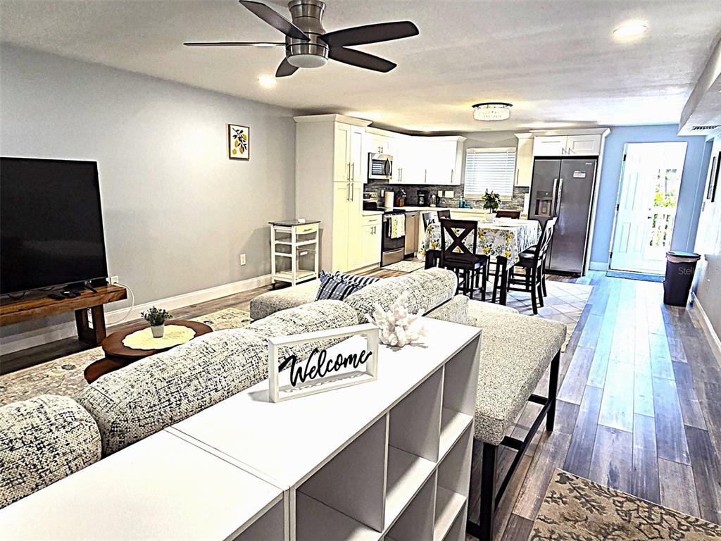 An open-concept living room and kitchen featuring light wood floors and white cabinetry — 5105 TANGERINE AVENUE S, GULFPORT, FL