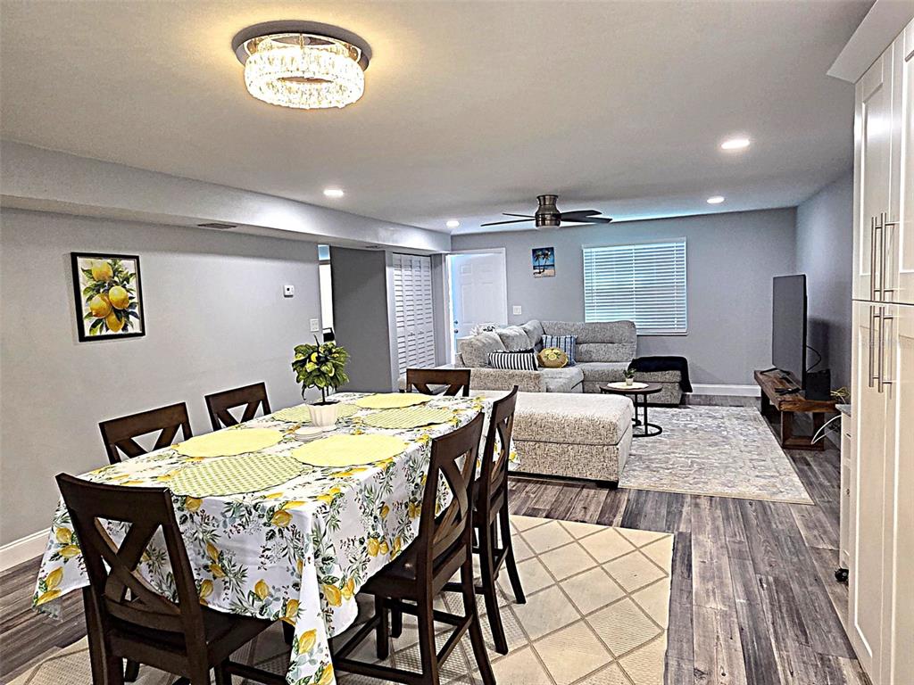 An open-concept living and dining area features gray walls, wood-look flooring, and a crystal chandelier — 5105 TANGERINE AVENUE S, GULFPORT, FL
