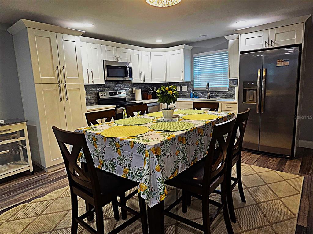A kitchen with white cabinets, stainless steel appliances, and a dining table with lemon-patterned cloth — 5105 TANGERINE AVENUE S, GULFPORT, FL