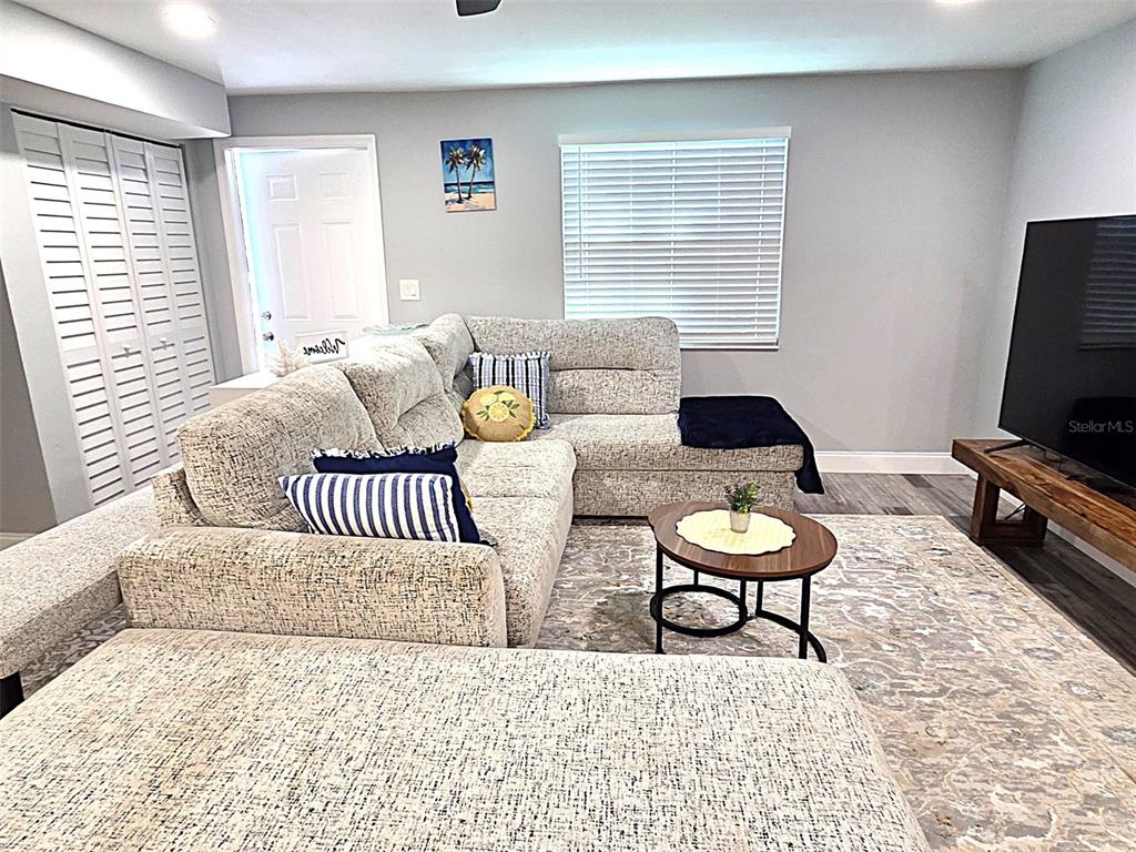 A living room features a large gray sectional sofa, a round coffee table, and a television — 5105 TANGERINE AVENUE S, GULFPORT, FL