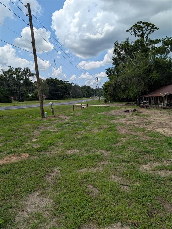 A grassy lot with a utility pole, a roadside mailbox, and a nearby building — 19063 N US HWY 441, REDDICK, FL
