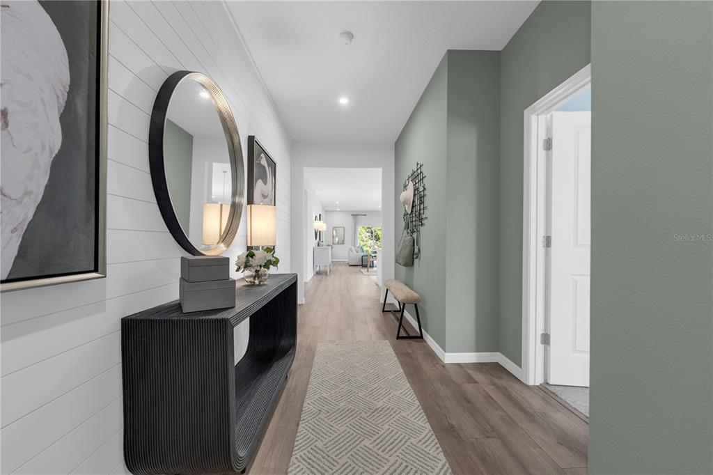 A modern hallway features white shiplap walls, a dark console table, and light wood flooring — 9194 HARRIS HAWK DRIVE, LEESBURG, FL