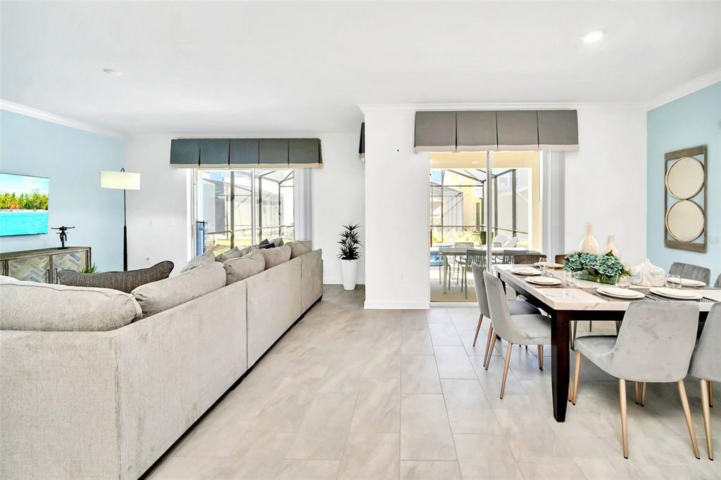 A living and dining area features light tile floors, gray furniture, and sliding glass doors — 2661 PETITION LANE, KISSIMMEE, FL