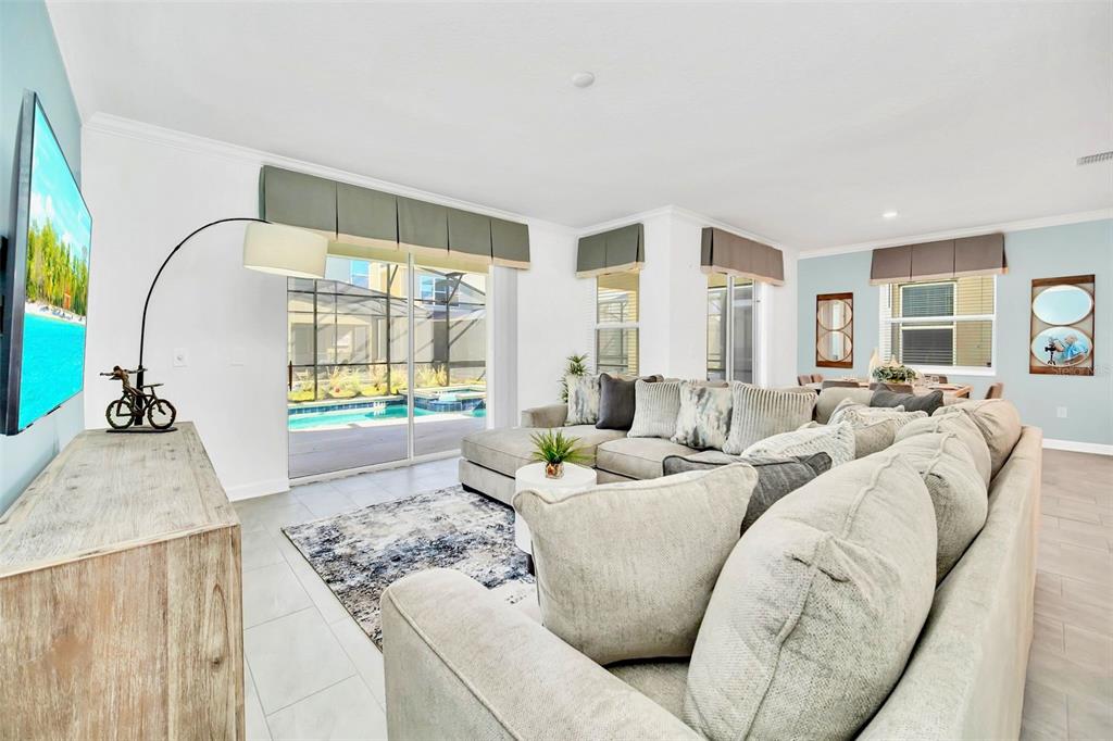 A living room features a large sectional sofa, a television, and sliding doors to a pool — 2661 PETITION LANE, KISSIMMEE, FL