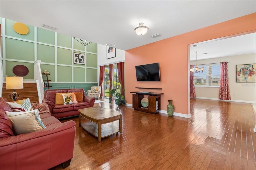 A living room with hardwood floors, a green paneled wall, and an orange accent wall — 13344 GRAHAM YARDEN, RIVERVIEW, FL