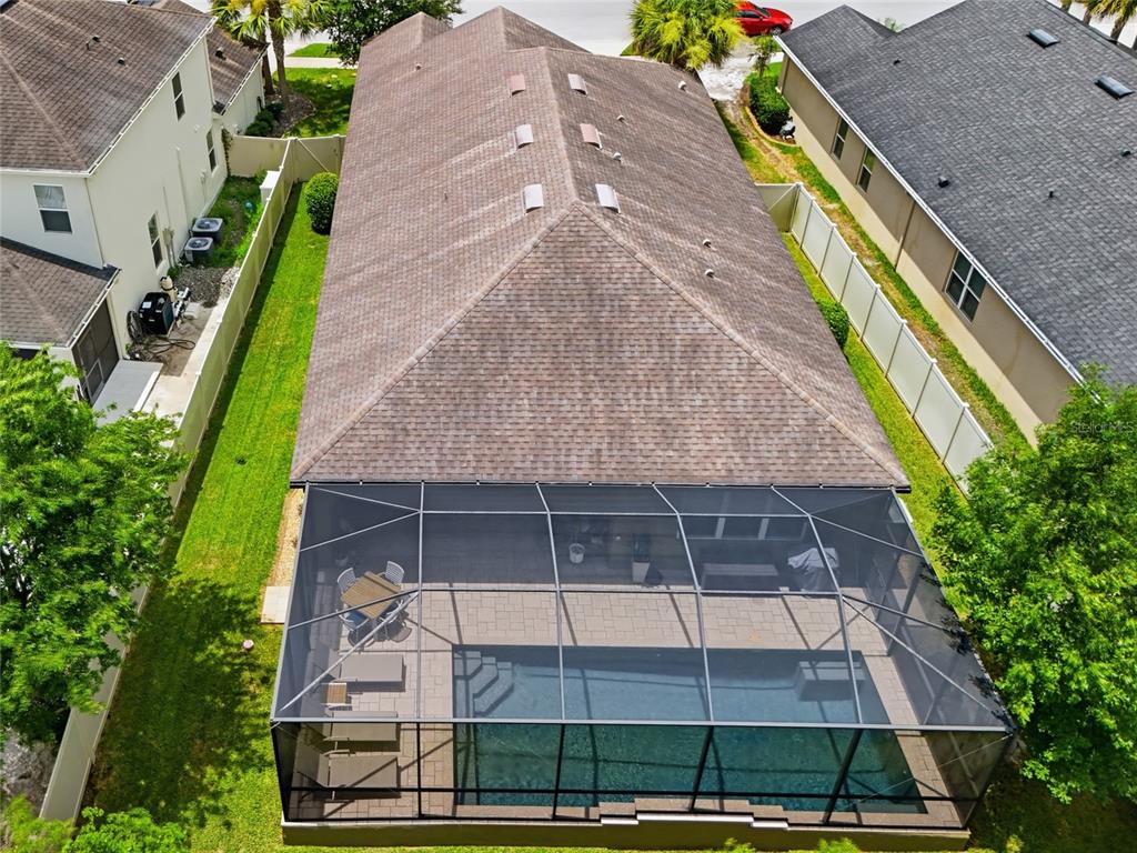 A screened-in swimming pool with a stone water feature and a paved patio area — 27035 CAROLINA ASTER DRIVE, WESLEY CHAPEL, FL