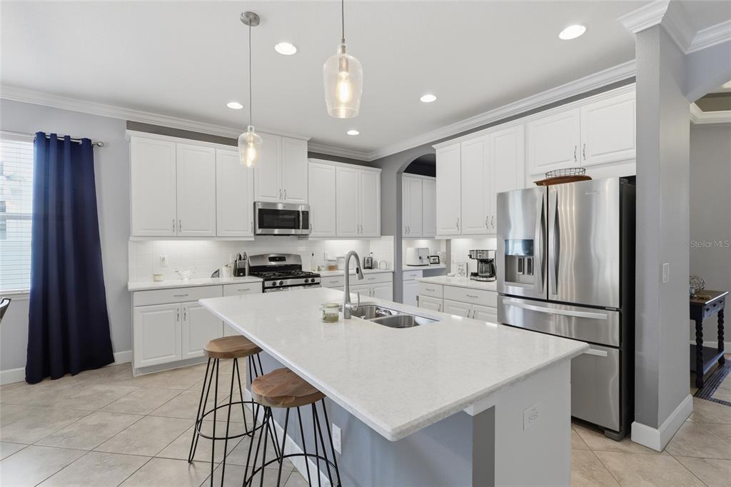 A foyer features light gray walls, tile flooring, a gray storage bench, and two framed paintings — 27035 CAROLINA ASTER DRIVE, WESLEY CHAPEL, FL
