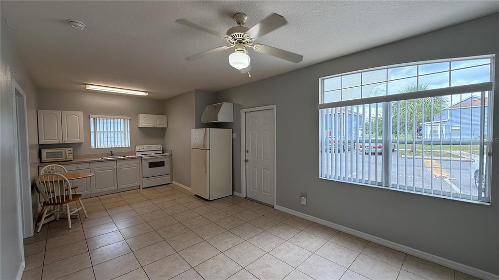 A kitchen with white cabinets, tile flooring, a ceiling fan, and a large window — 627 ORCHID DRIVE, DAVENPORT, FL
