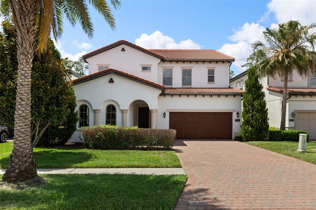A two-story house with a red tile roof, white stucco exterior, and a brick driveway — 10396 ROYAL CYPRESS WAY, ORLANDO, FL