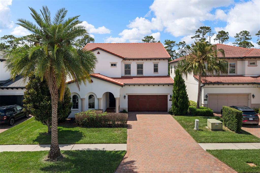 A house exterior features a brick driveway, a wooden garage door, and a covered entryway — 10396 ROYAL CYPRESS WAY, ORLANDO, FL
