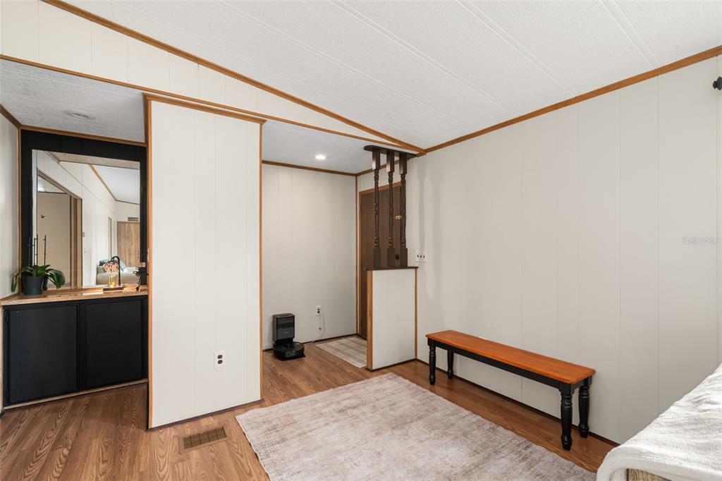An interior room features wood-look flooring, white paneled walls, a wooden bench, and a mirror — 906 WHATLEY COURT, SEBRING, FL