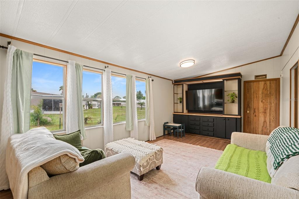 A living room features light-colored walls, a large entertainment center, and windows with green curtains — 906 WHATLEY COURT, SEBRING, FL