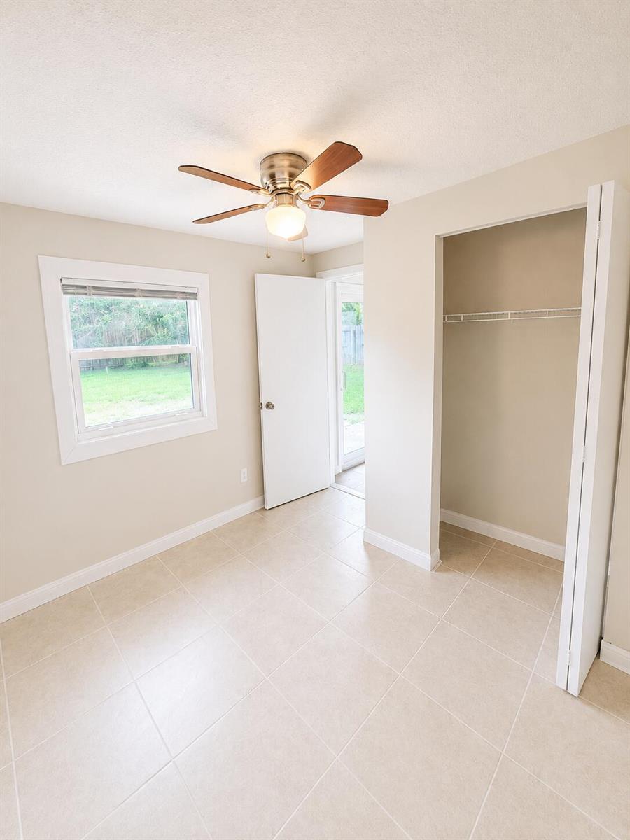 A bedroom with beige walls, tile flooring, a ceiling fan, and an open closet — 3666 SW Rivera Street, FL 34953, FL