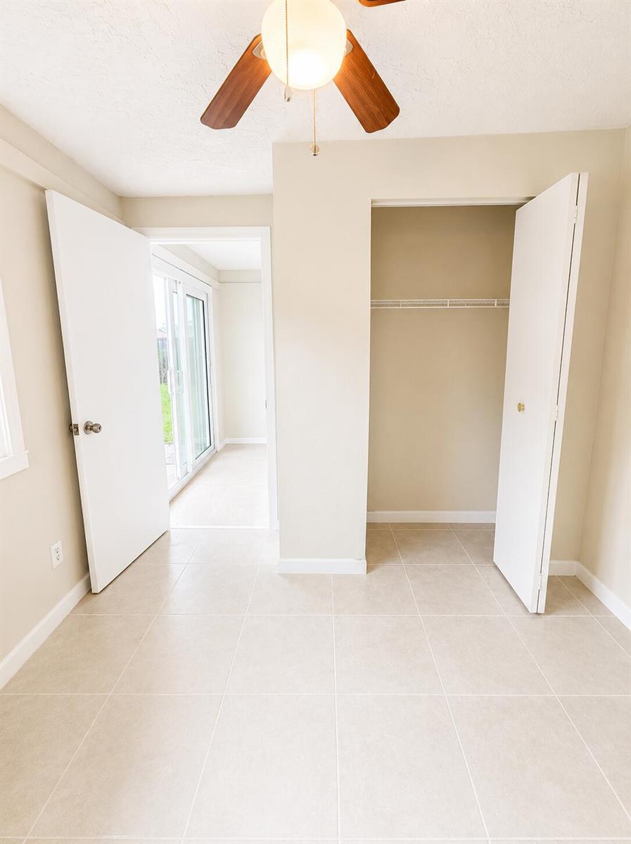 A room with beige tile flooring, a ceiling fan, a closet, and a doorway leading outside — 3666 SW Rivera Street, FL 34953, FL