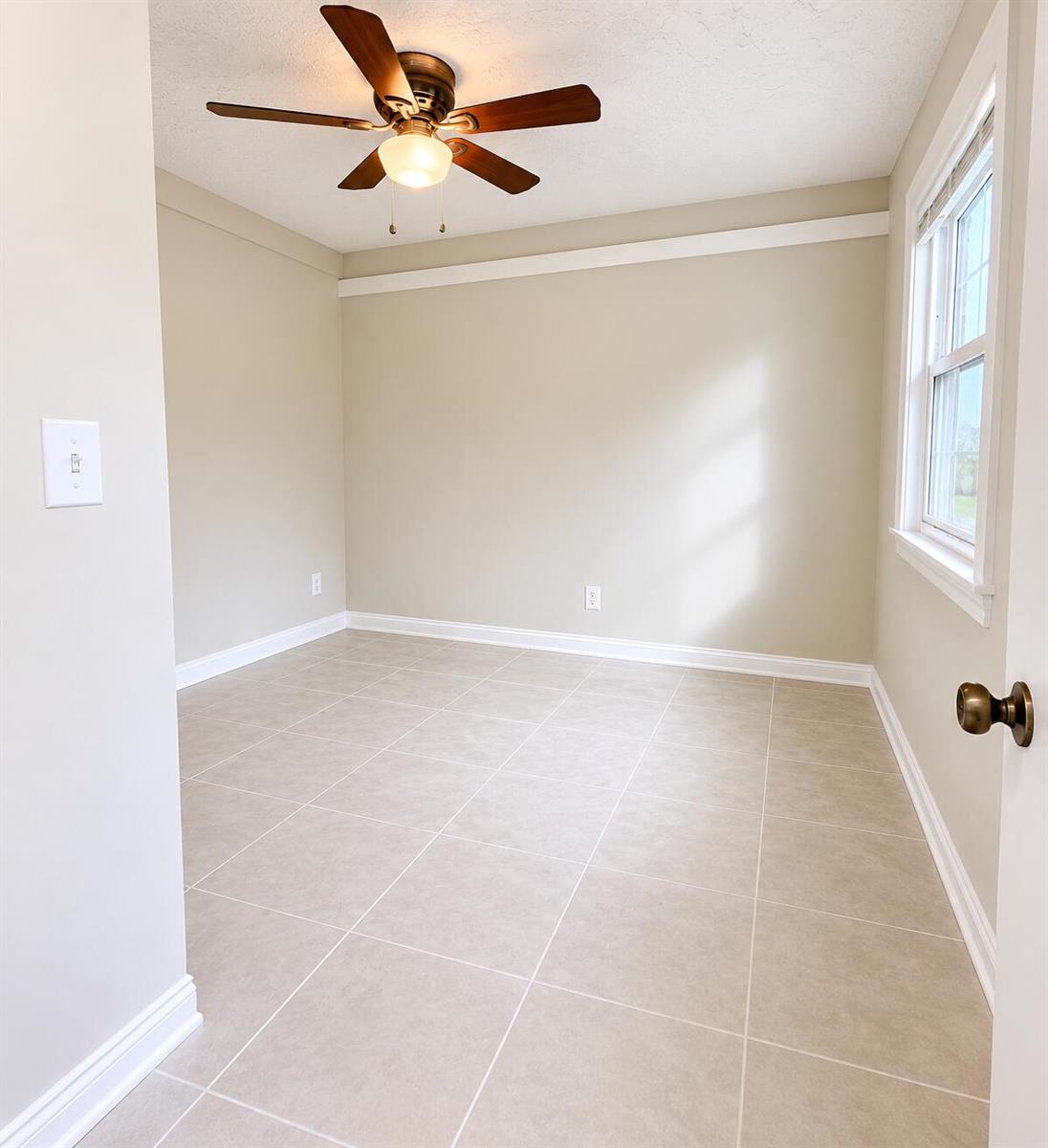 An empty room features beige walls, tile flooring, a ceiling fan, and a window — 3666 SW Rivera Street, FL 34953, FL