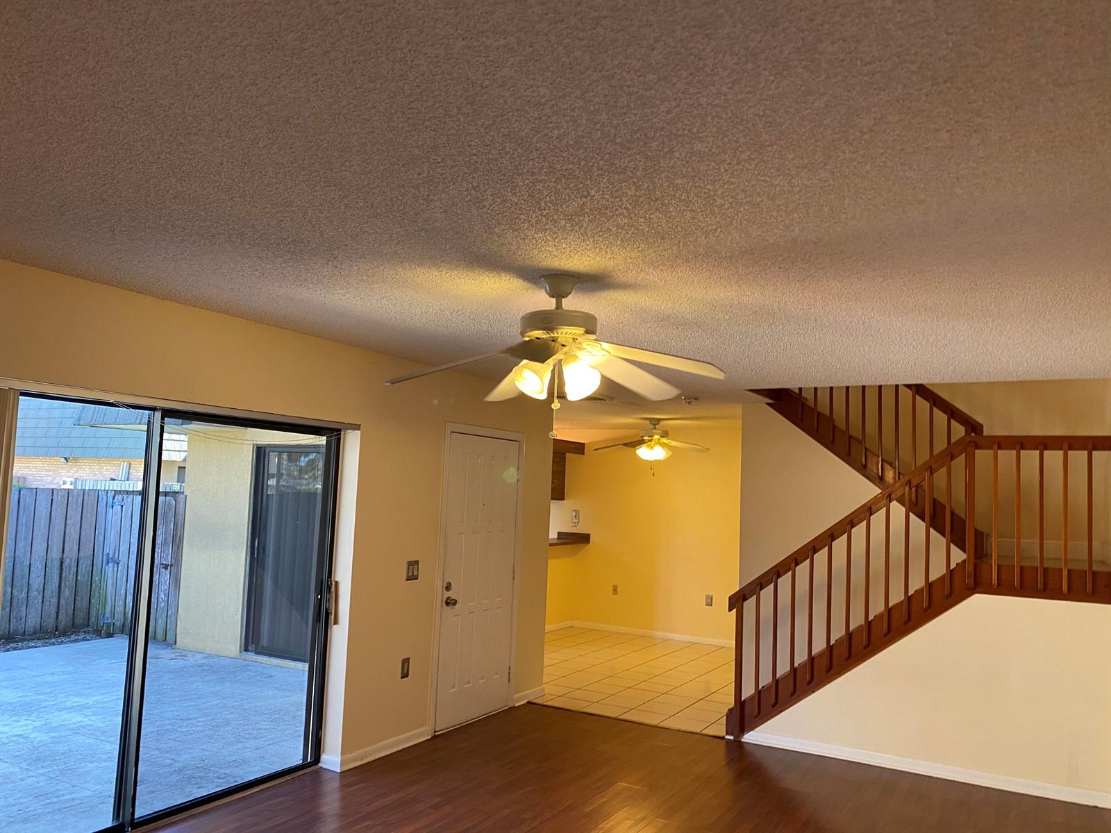 A living room with wood flooring, a ceiling fan, a staircase, and a sliding glass door — 1603 16th Way, West Palm Beach FL 33407, WEST PALM BEACH, FL