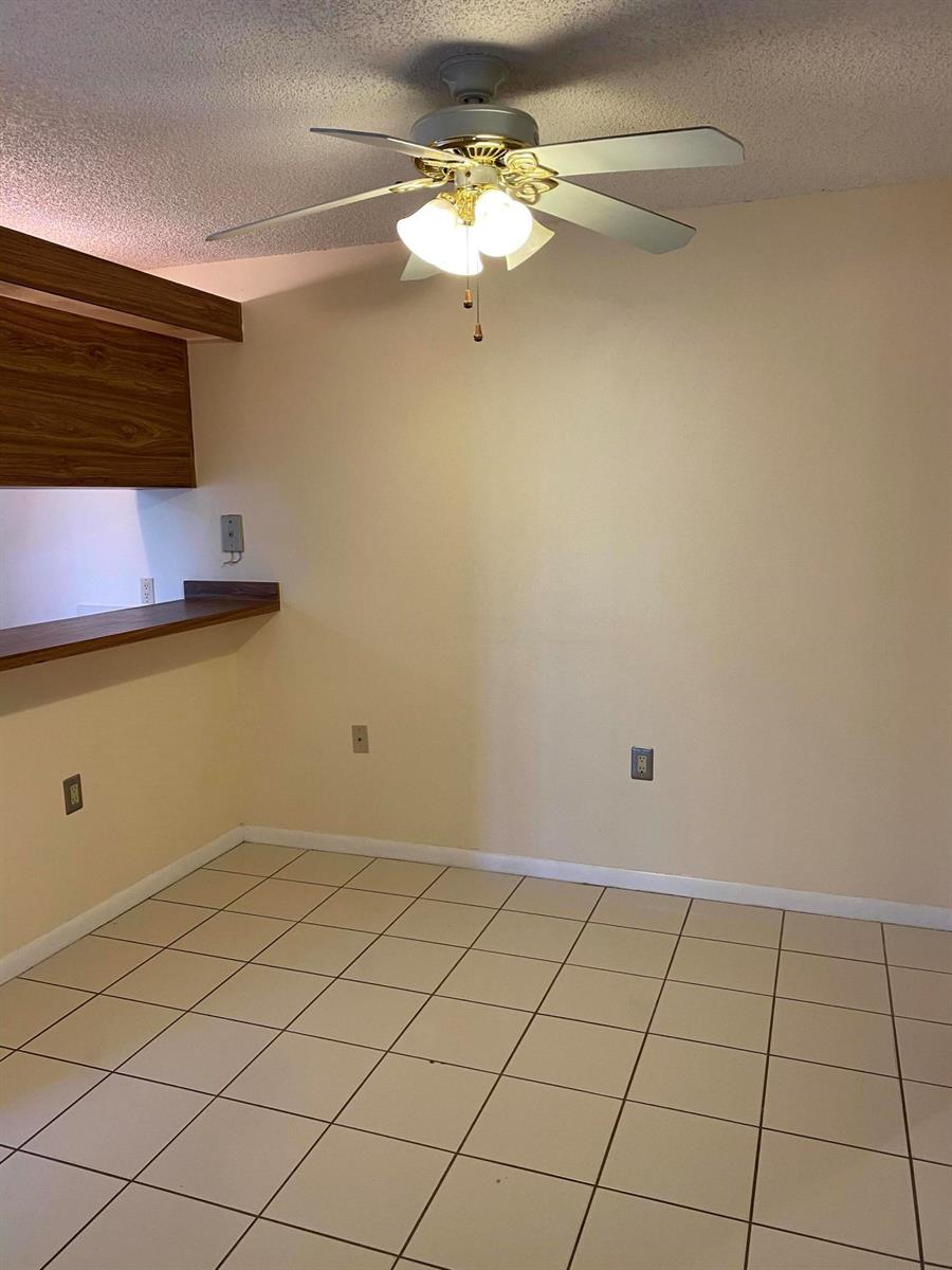 A dining area features beige tile flooring, a ceiling fan, and a wooden breakfast bar — 1603 16th Way, West Palm Beach FL 33407, WEST PALM BEACH, FL