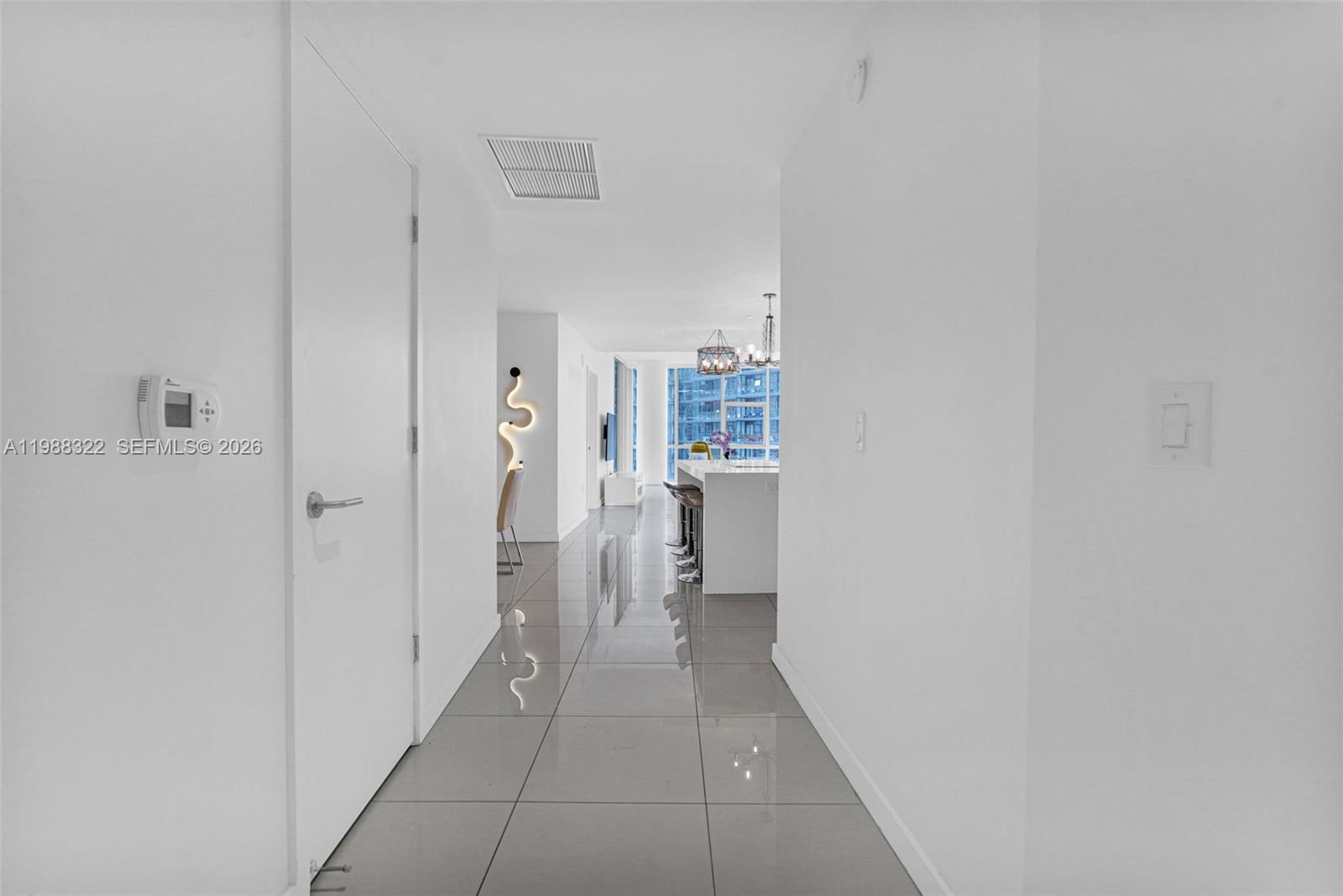 A hallway with gray tile flooring leads toward a kitchen with a white island — 851 NE 1st Ave # 2912, Miami FL 33132, MIAMI, FL