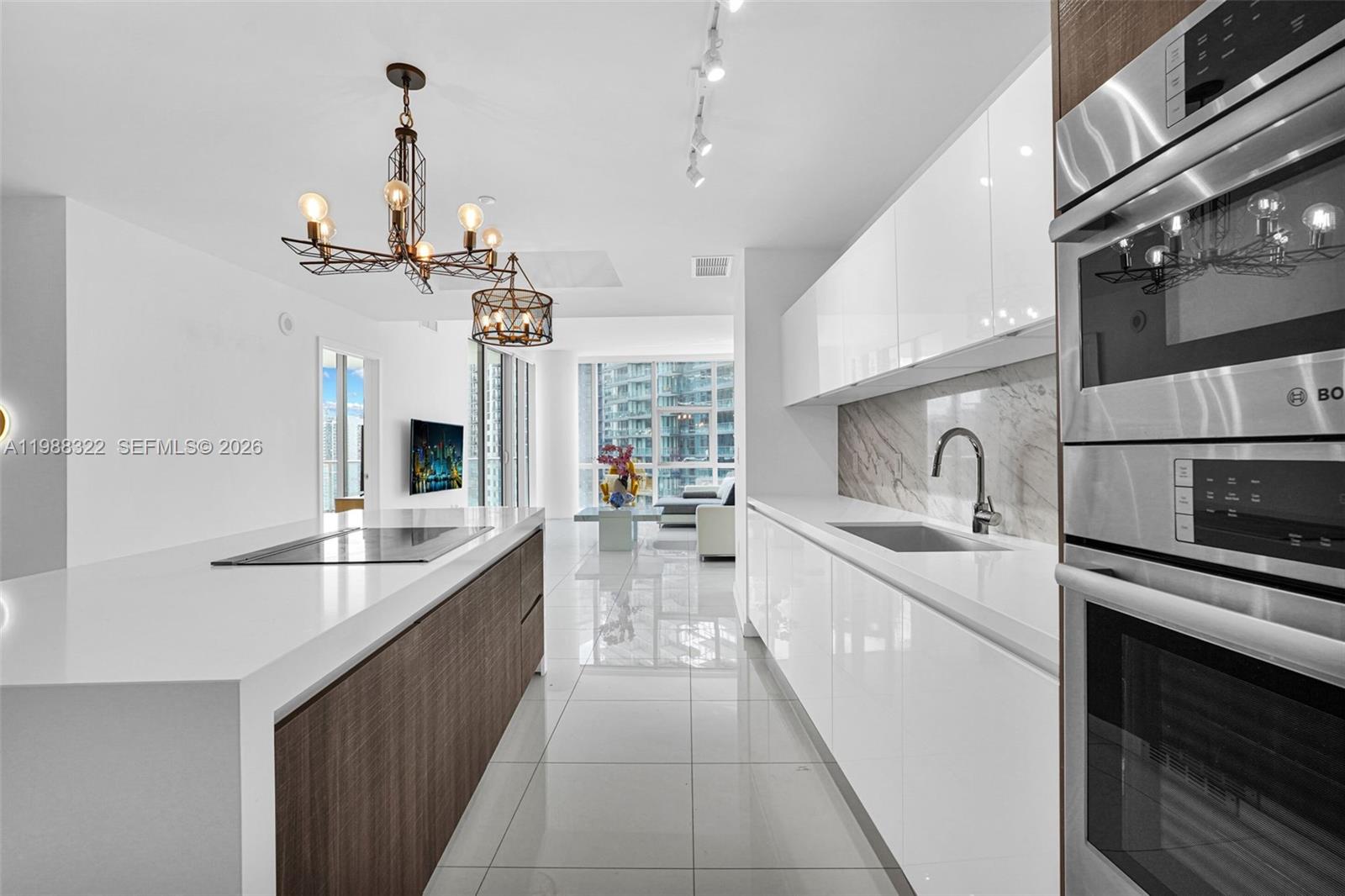 A modern kitchen features white cabinetry, a wood-paneled island, and stainless steel appliances — 851 NE 1st Ave # 2912, Miami FL 33132, MIAMI, FL