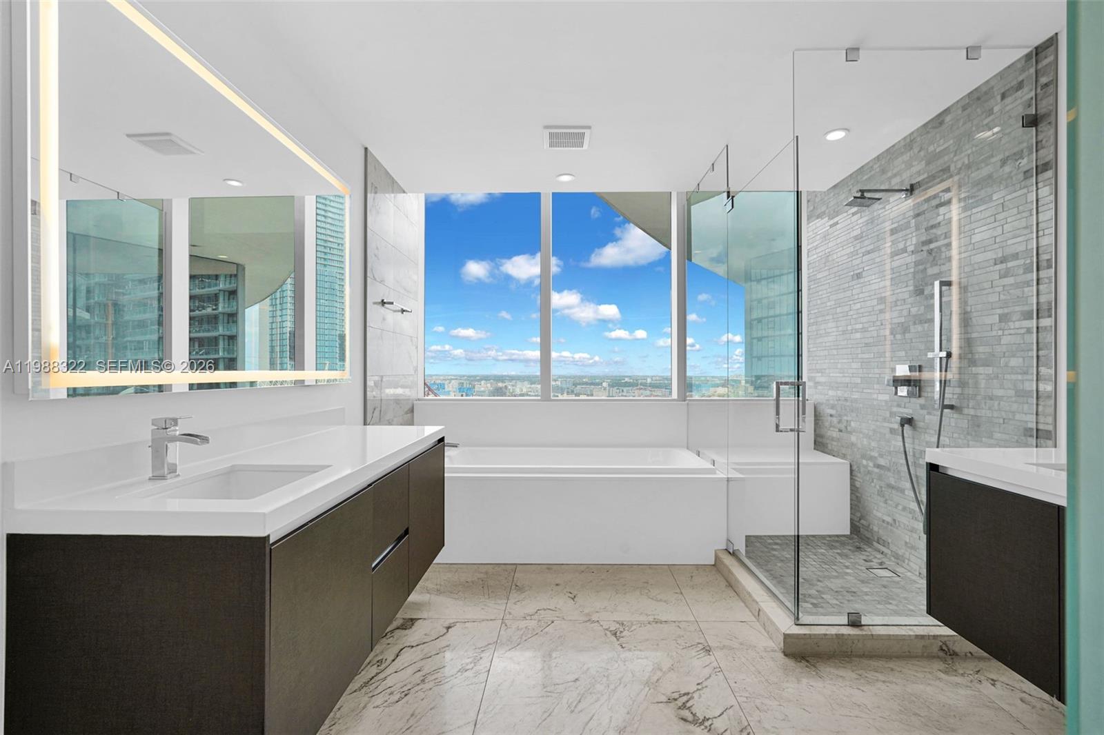 A modern bathroom features a floating vanity, a soaking tub, and a glass-enclosed walk-in shower — 851 NE 1st Ave # 2912, Miami FL 33132, MIAMI, FL