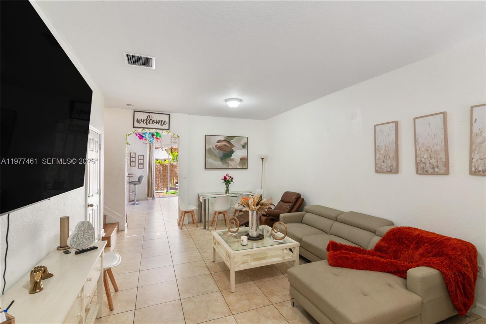 A living room with tiled floors, a beige sectional sofa, and a dining area — 12958 SW 135th St, Miami FL 33186, MIAMI, FL