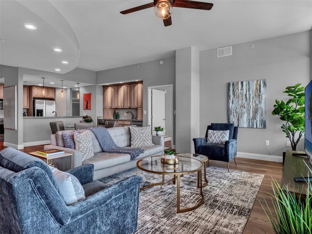 A living room with a grey sofa, blue armchairs, and a glass coffee table — 525 E JACKSON STREET UNIT P4, ORLANDO, FL