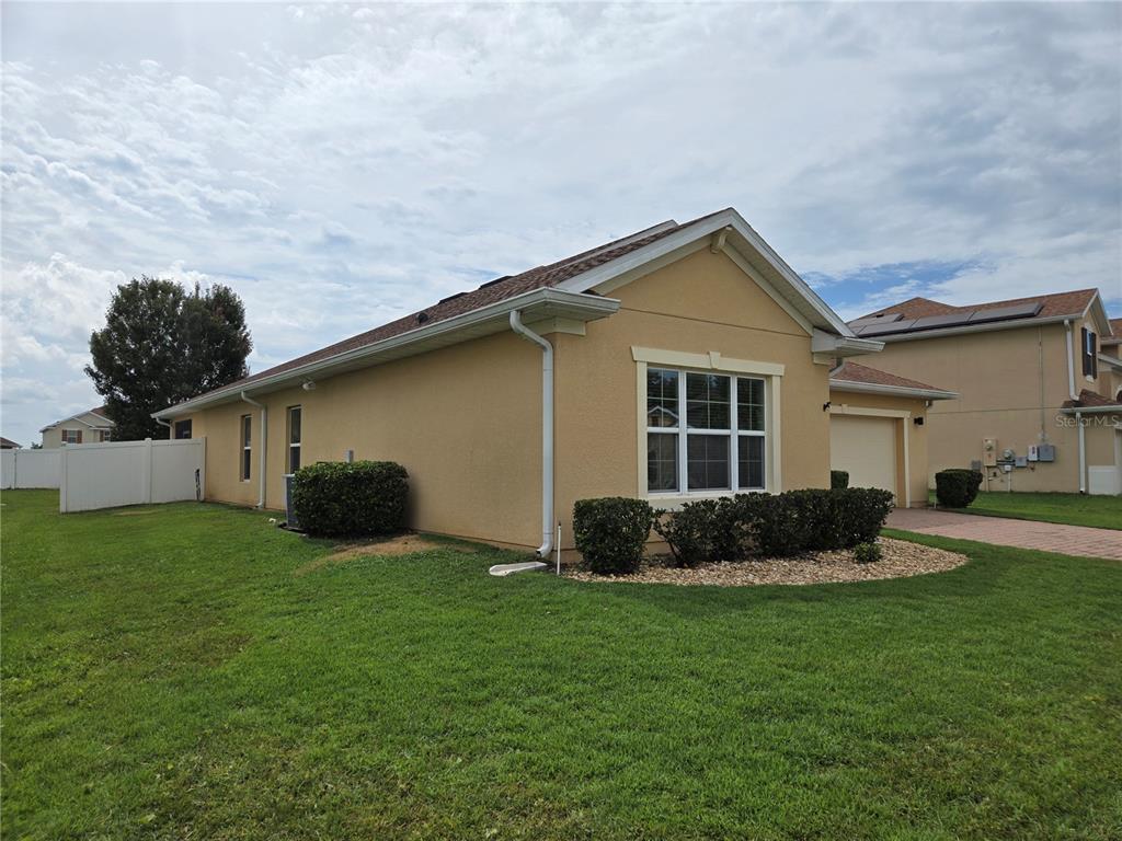 A tan, single-story house with a gabled roof, a garage, and a landscaped front yard — 2246 WAUKEGAN DRIVE, KISSIMMEE, FL