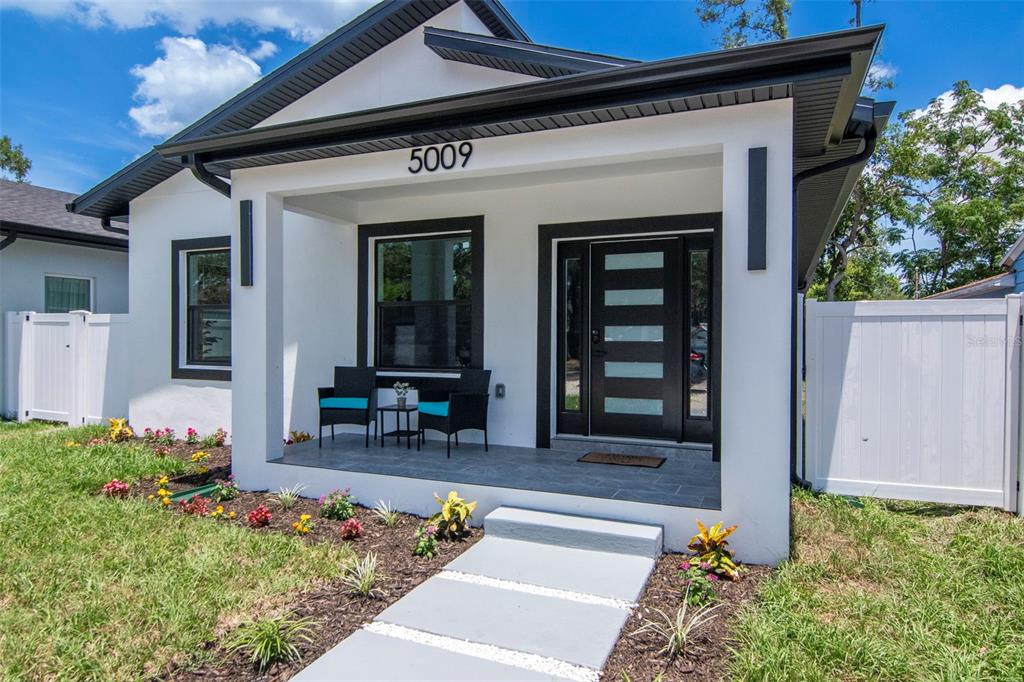 A modern white house with black trim features a front porch and a paved walkway — 5009 9TH AVENUE S, GULFPORT, FL