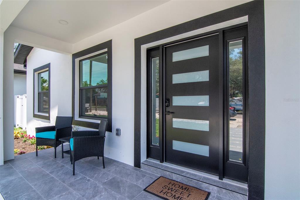 A modern front porch features a black door with glass panels and two wicker chairs — 5009 9TH AVENUE S, GULFPORT, FL