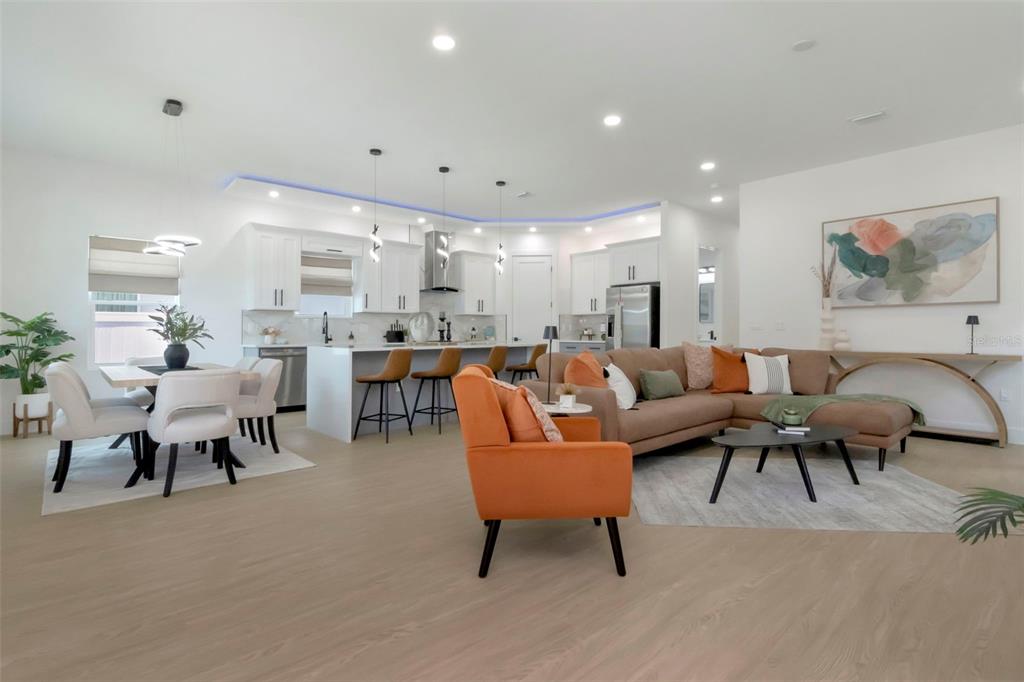 An open-concept living room and kitchen featuring light wood flooring and modern furniture — 5009 9TH AVENUE S, GULFPORT, FL