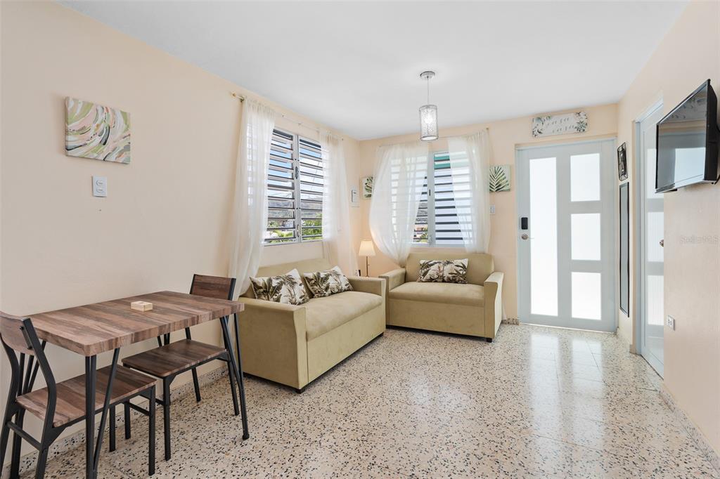 A living room features two beige sofas, a dining table, and tile flooring — Solar 124 CALLE 4, YAUCO, PR