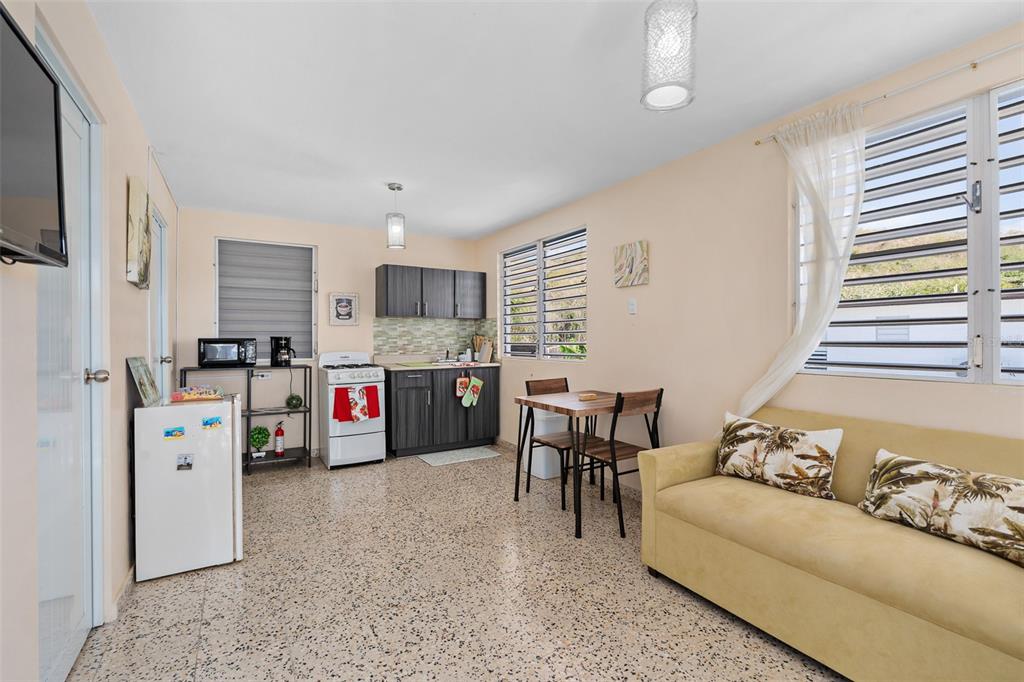 A small studio apartment featuring a kitchenette, dining table, and a yellow sofa — Solar 124 CALLE 4, YAUCO, PR