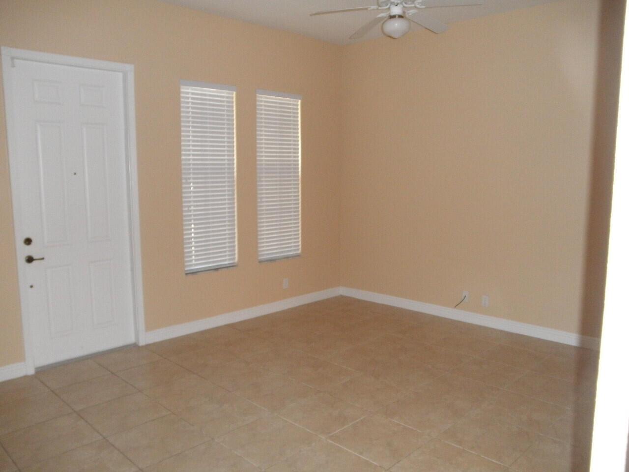 An empty room with tan walls, tile flooring, two windows with blinds, and a ceiling fan — BOCA RATON, FL