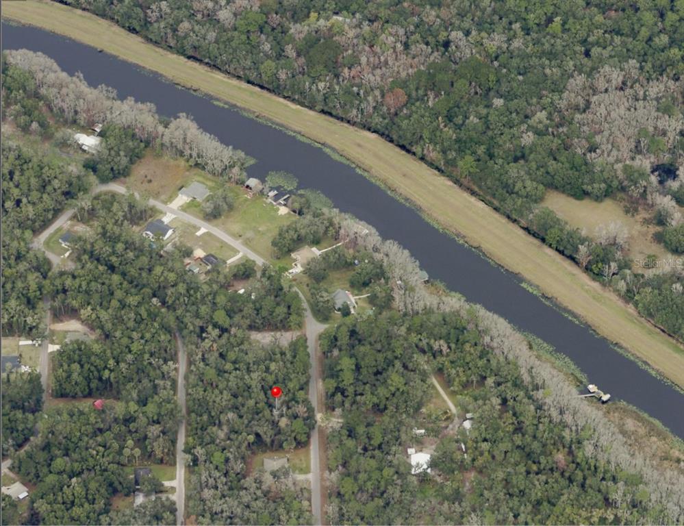 An aerial view shows a wooded residential lot marked with a red pin near water — 0 SEQUOIA DRIVE, OCKLAWAHA, FL