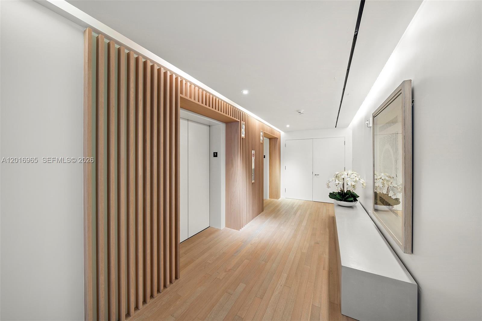 A modern elevator lobby features light wood slat walls, hardwood flooring, and a white console — 2901 Collins Ave # 901, Miami Beach FL 33140, MIAMI BEACH, FL