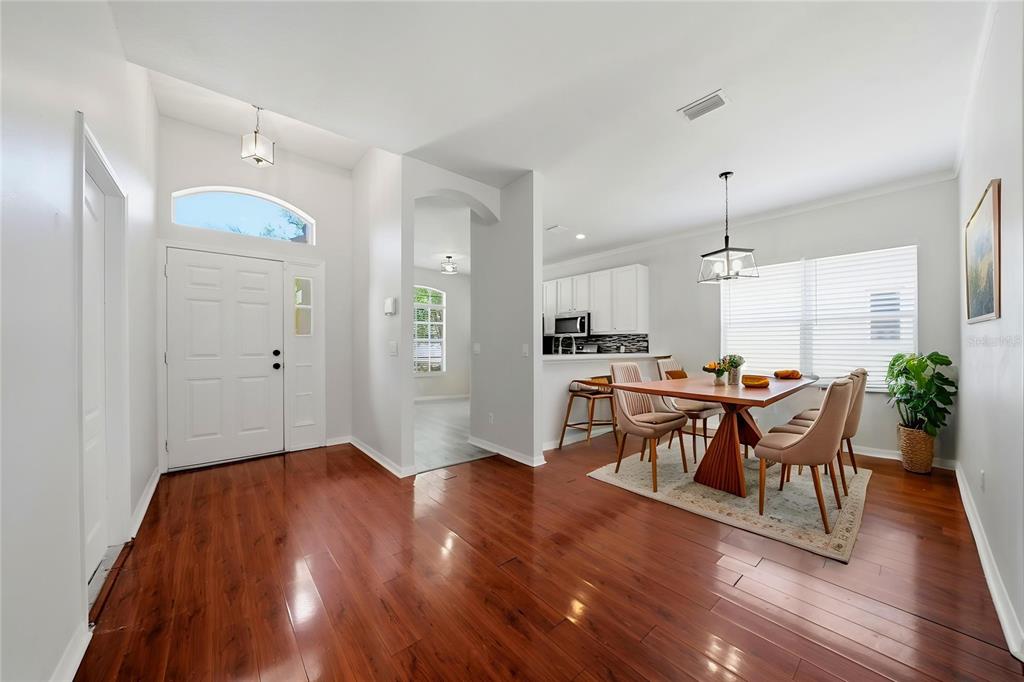 A bright entryway with hardwood floors leads to a dining area and an open kitchen — 403 LAGUNA MILL DRIVE, RUSKIN, FL