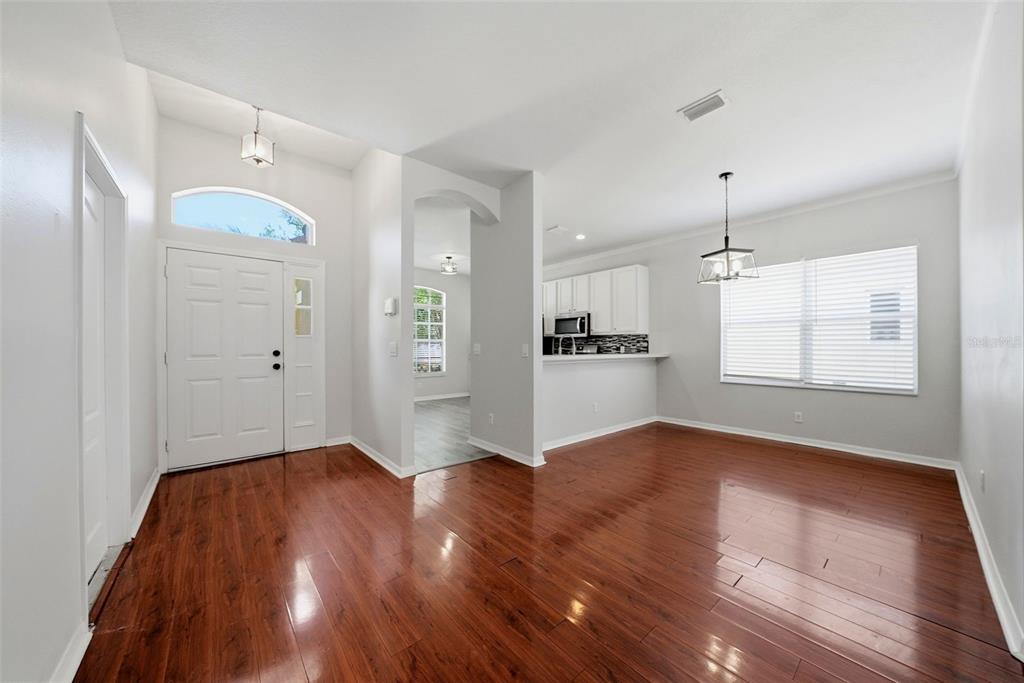 A bright entryway with hardwood floors leads to an open dining area and kitchen — 403 LAGUNA MILL DRIVE, RUSKIN, FL