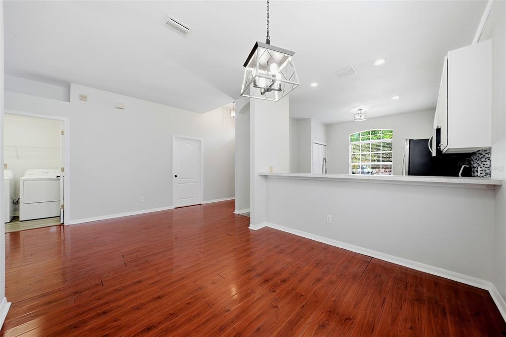 A dining area with hardwood floors, a pendant light, and an open view into the kitchen — 403 LAGUNA MILL DRIVE, RUSKIN, FL