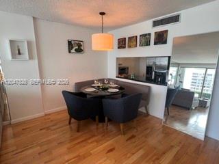 A dining area features a round table, dark chairs, a banquette, and a large mirror — 199 Ocean Lane Dr # 903, Key Biscayne FL 33149, KEY BISCAYNE, FL