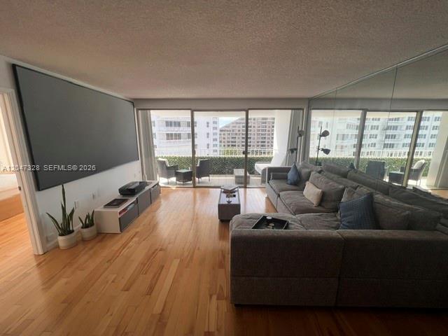 A living room features hardwood floors, a large projector screen, and a sectional sofa — 199 Ocean Lane Dr # 903, Key Biscayne FL 33149, KEY BISCAYNE, FL