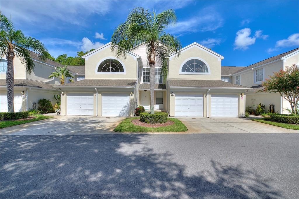 A two-story townhouse exterior features four garage doors, arched windows, and a central palm tree — 5999 LAKE POINTE DRIVE UNIT 608, ORLANDO, FL