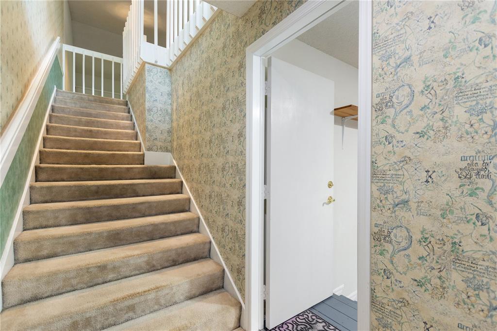 A carpeted staircase with white railings sits beside a doorway featuring patterned wallpaper — 5999 LAKE POINTE DRIVE UNIT 608, ORLANDO, FL