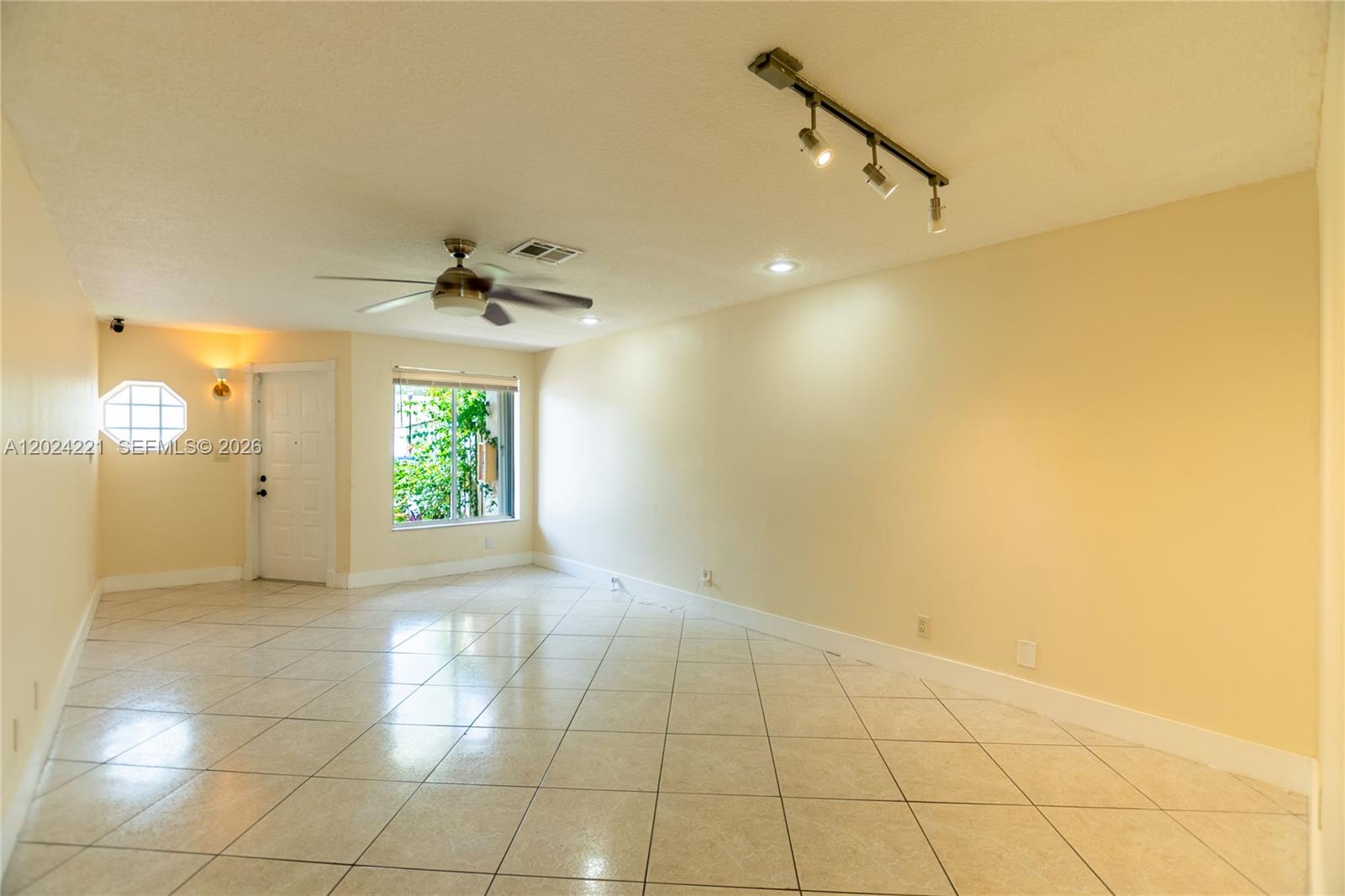 An empty living room features beige walls, light-colored tile flooring, a ceiling fan, and track lighting — 9803 NW 37th St, Sunrise FL 33351, SUNRISE, FL