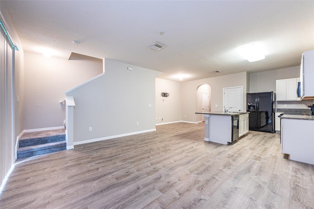 An open-concept living area features wood-look flooring, a staircase, and a kitchen with an island — 8908 INDIGO TRAIL LOOP, RIVERVIEW, FL