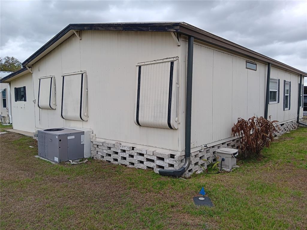 The exterior of a manufactured home features beige siding, metal window awnings, and a block foundation — 37536 AMIGO DRIVE, ZEPHYRHILLS, FL