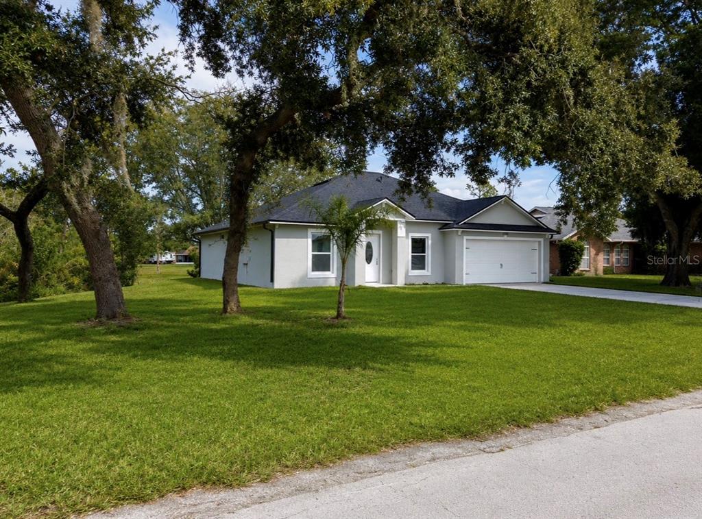 A single-story house with a white exterior, dark roof, and attached garage sits on a lawn — 1780 CONVERSE COURT, DELTONA, FL
